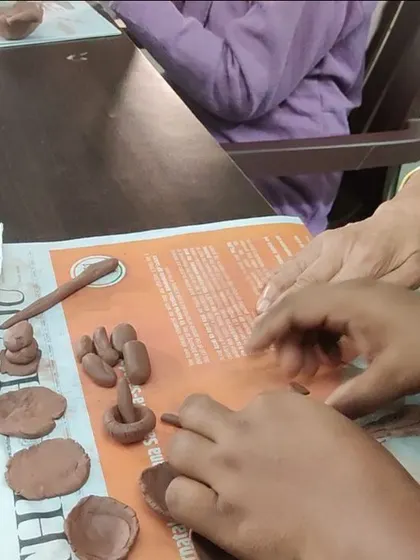 Hands of different generations working together with clay. These sessions can be a beautiful point of connection, where caregivers and seniors share a creative, non verbal experience.