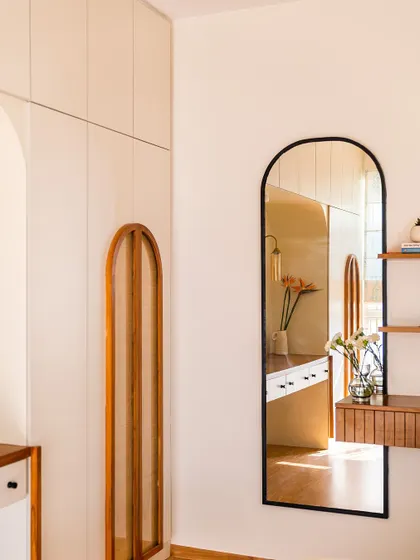 The arched mirror in this bedroom reflects the arched cane details on the wardrobe, creating a harmonious and elegant design story.