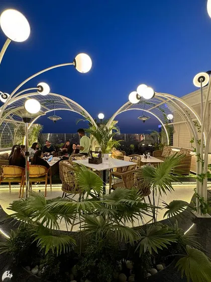 The rooftop terrace at Tipsy Town features biophilic design elements, including sculptural, tree-like light fixtures and arched trellises. These structures create a whimsical garden atmosphere, bringing nature into the urban environment.