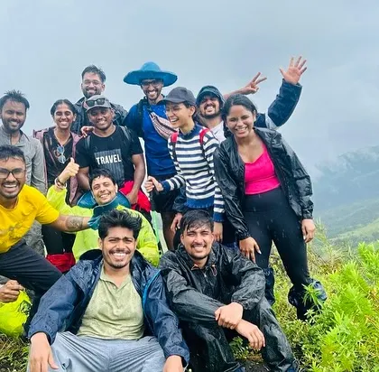 A group selfie on a lush green mountain, with everyone smiling and having fun. These are the candid moments that make our trips special.