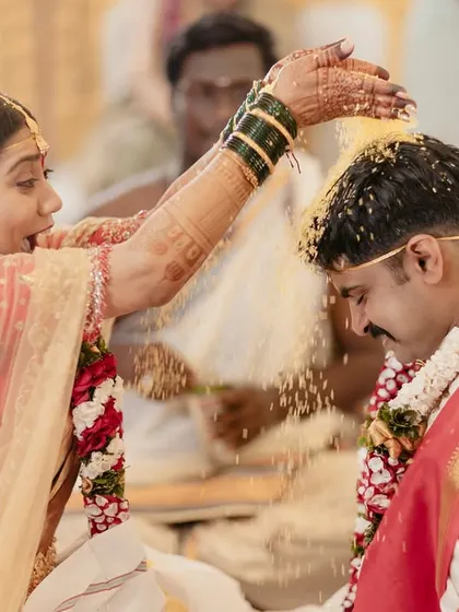 The bride joyfully showers her groom with rice during the Talambralu ceremony, a playful and significant South Indian wedding ritual.