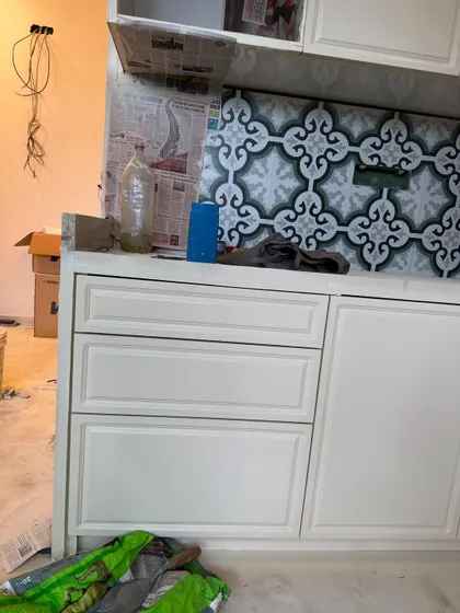 A close-up of the shaker-style cabinet drawers and the intricate backsplash tiles during the kitchen installation.