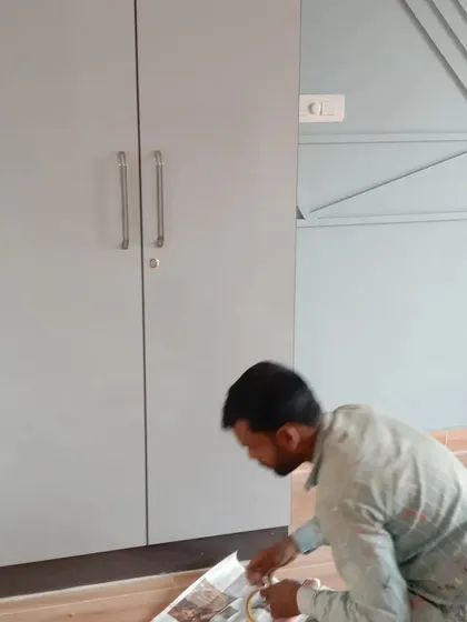 Attention to detail during preparation. Our painter carefully masks the floor area to protect the wooden laminate before painting the wall and wardrobe.