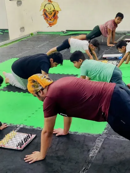 Who says you can't train your mind and body at the same time? Here, our students hold a plank position while playing chess, a unique drill to build mental and physical endurance.