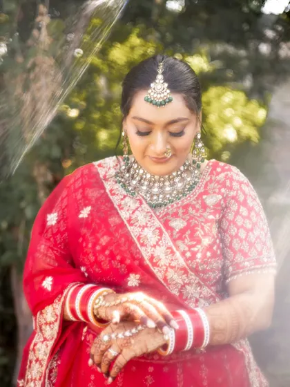 A quiet, reflective moment. The soft focus highlights the intricate details of her henna and the shimmering texture of her makeup.