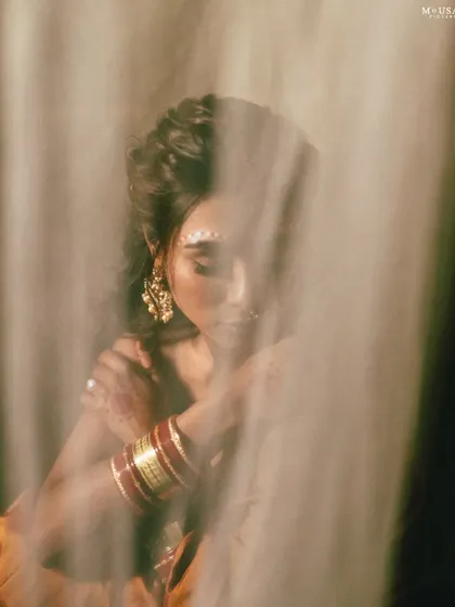 An ethereal portrait of a model as an Odia bride, shot through a translucent curtain. The soft, diffused light creates a dreamy and mysterious effect.