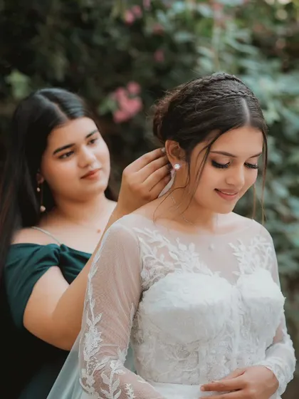 A sister's helping hand. A beautiful moment between the bride and her bridesmaid as she gets her final touches. The braided hairstyle is so unique and elegant.