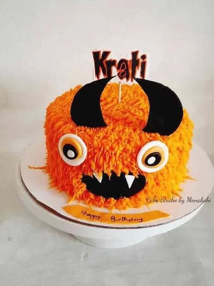 A fun and furry monster themed cake. The bright orange "fur" is piped with buttercream, and the cake is finished with big eyes and horns.