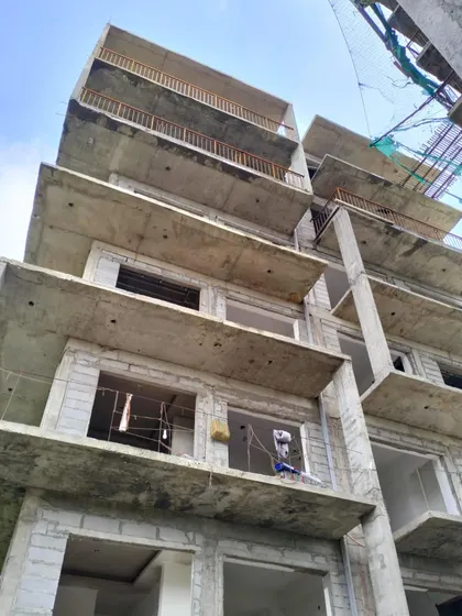 A low-angle shot of an apartment building under construction, emphasizing the cantilevered concrete slabs that will become spacious balconies.