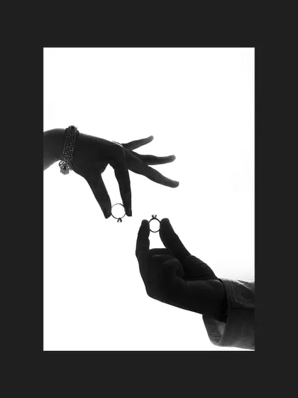A creative black and white silhouette of the couple's hands holding their wedding rings.