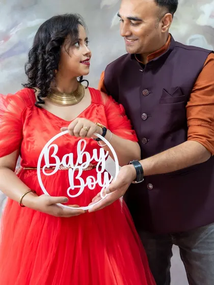 A happy couple portrait with a "Baby Boy" sign, capturing their shared excitement.
