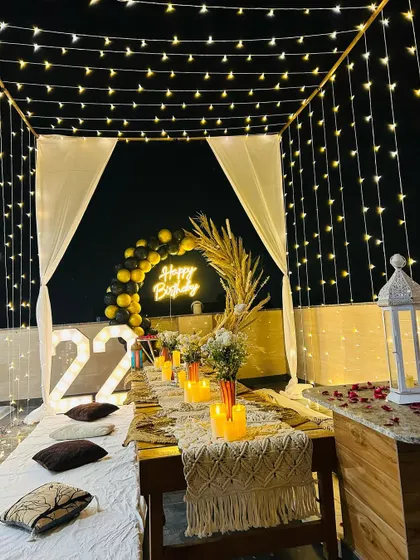 A view of our terrace dinner setup under a canopy of fairy lights. This image highlights the low seating arrangement with a macrame table runner and candles, perfect for an intimate birthday dinner.