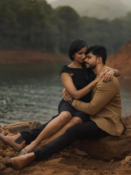 An intimate pre-wedding portrait by the water's edge. The moody lighting and natural landscape create a beautifully romantic and slightly dramatic feel, perfect for showcasing a deep connection.