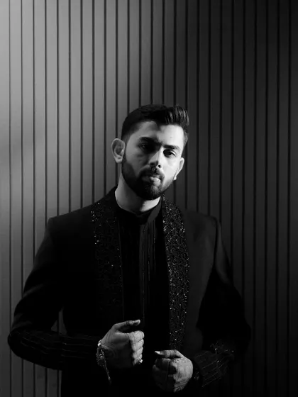 A confident and stylish portrait of the groom before his Sangeet performance. The black and white treatment and linear background add a modern, graphic quality to the shot.
