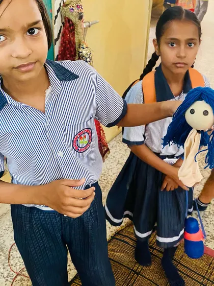 Two proud students from J.B. Academy show the puppets they made during the first day of the workshop.