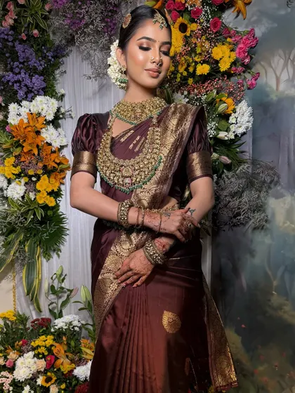 A full-length view of the bride against a floral backdrop. The drape of the saree creates a beautiful, flowing silhouette.
