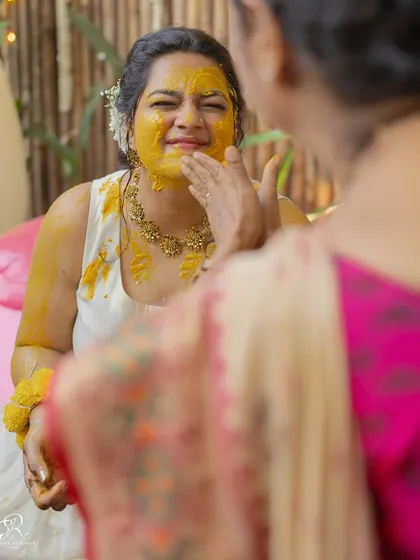 A close-up of the bride getting haldi applied by a loved one, a moment of gentle tradition.