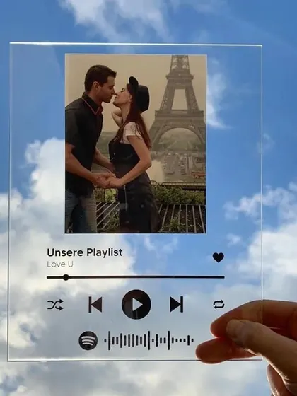 This image showcases the sleek, transparent design of the personalized music plaque. It looks almost invisible against the sky, highlighting the custom photo and song details.