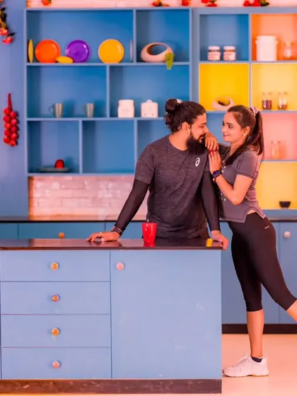 A romantic, intimate moment in a colorful kitchen. The neon sign "The Secret Ingredient is Love" adds a fun and meaningful touch to this pre-wedding photo.