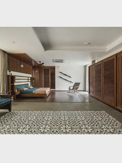 This bedroom showcases a clean, minimalist aesthetic with louvered wooden wardrobe doors and a patterned tile area rug. The design prioritizes simplicity and functionality, creating a calm and uncluttered space.