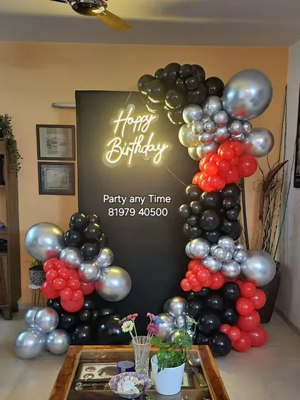 A unique and trendy design with an abstract arrangement of red, black, and silver balloons against a black backdrop with a neon sign.