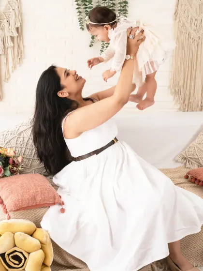Up in the air! A mother's playful lift brings out the biggest smiles from her little one.