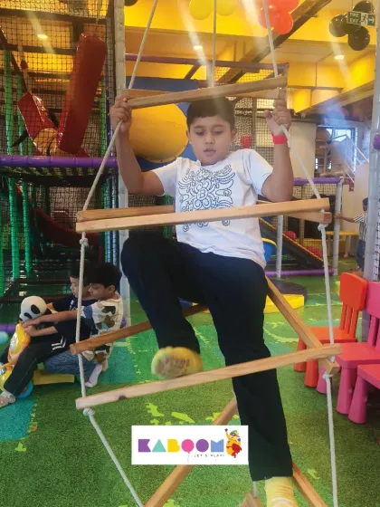 This young adventurer is tackling our rope ladder, a fun challenge that helps develop coordination and strength.