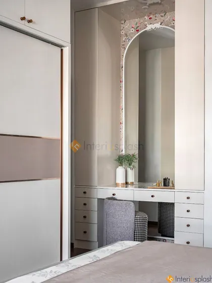This bedroom design includes a built-in vanity table with drawers, seamlessly integrated between two wardrobe units. The large arched mirror makes the dressing area feel spacious and elegant.