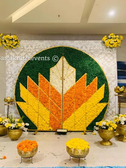 A stunning floral mosaic backdrop in the shape of a lotus. We used petals of yellow, orange, white, and pink flowers to create this large, colorful centerpiece for a festive celebration.