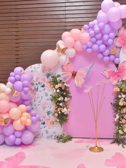 This butterfly decor features a stunning combination of floral arrangements and balloon garlands on custom-built panels.