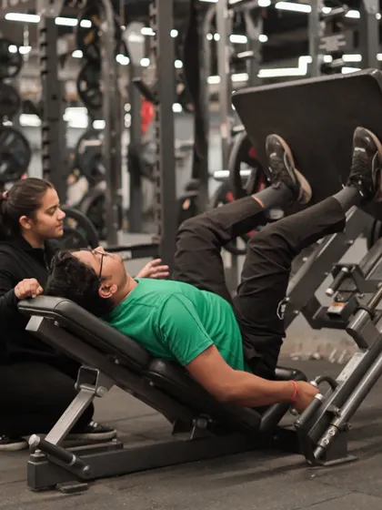 I ensure every client is safe and effective in their workouts. Here, a trainer spots a client on the leg press, providing encouragement and ensuring correct technique.