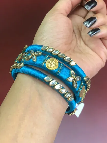 This set of three blue silk thread bangles is adorned with kundan stones and temple coins, offering a traditional look in a vibrant colour.