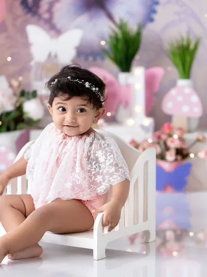 A beautiful butterfly-themed setup for a first birthday. This little one is sitting pretty on her miniature bed.