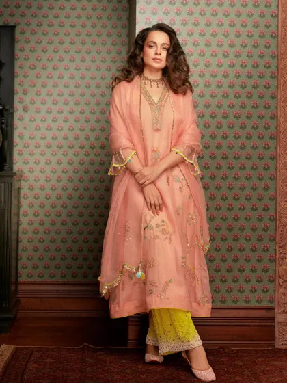 A full-length view of Kangana's peach and yellow suit. The pop of yellow in the pants adds a fresh, unexpected twist to the classic look.