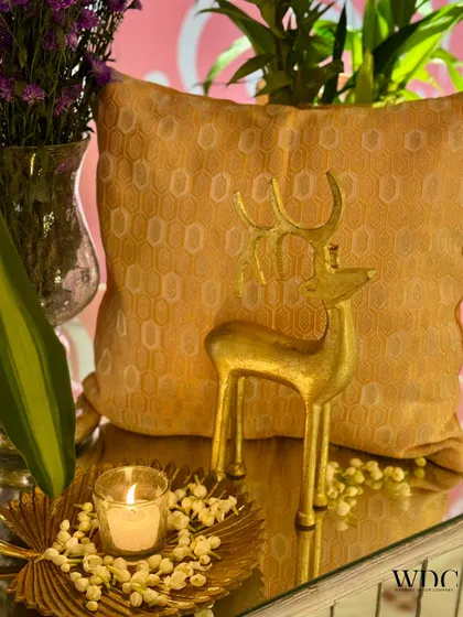 A small, elegant detail. A golden reindeer figurine and a candle on a leaf-shaped tray add a touch of whimsy and warmth to a tabletop.