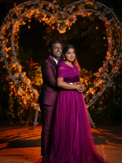 A beautiful nighttime portrait of a couple in matching wine-colored outfits. The floral heart-shaped arch adds to the romantic atmosphere of the pre-wedding shoot.