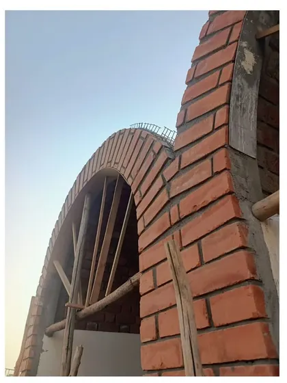 A close-up of the exposed brick arch during construction, showcasing the traditional building techniques used to create these modern forms.