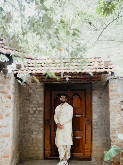 The groom standing before a traditional wooden door, ready for his wedding ceremony.