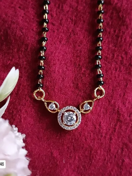This modern mangalsutra design features a central solitaire-style American diamond in a circular halo setting. It's a classic and timeless piece, crafted from 92.5 silver with gold plating.