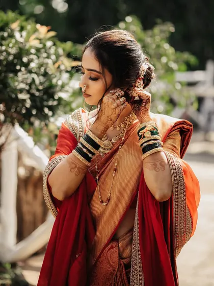 The bride adjusts her traditional jewelry, a candid moment captured during her getting-ready process.