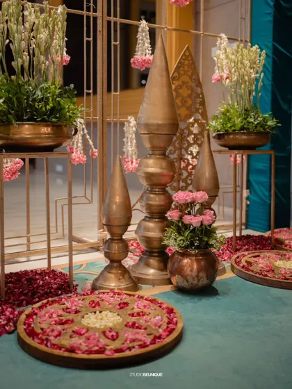A corner decorated with traditional brass spires, floral rangolis, and hanging flower strings. This shows my expertise in creating authentic, traditional Indian decor.