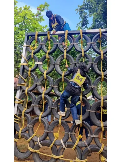 Participants tackling a tire wall obstacle. Our leadership camps involve challenging physical activities that build confidence.