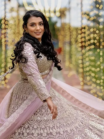 A bride twirling in her beautiful lehenga at an outdoor Sangeet, with a tunnel of fairy lights creating a stunning visual effect.