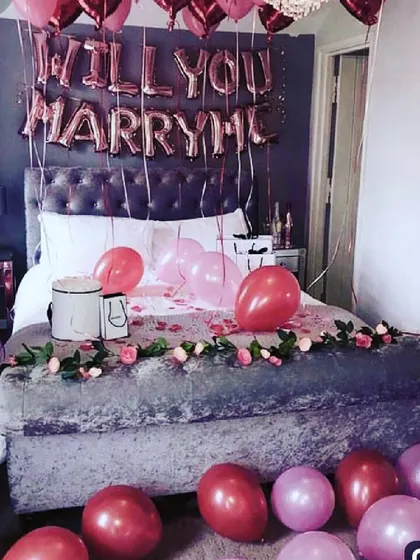 I can help you ask the big question with a complete proposal room setup. This decoration includes "WILL YOU MARRY ME" foil balloons above the bed, a romantic rose garland, and color-coordinated balloons to fill the space.
