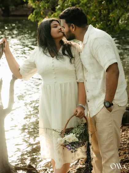 A sweet, intimate moment during a pre-wedding shoot by the lake, highlighting the couple's affection.