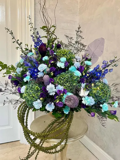 This arrangement showcases my love for complex color palettes. I juxtaposed sea green hydrangeas with deep purples and cool blues to create a chic, harmonious design that feels both immaculate and full of life, perfect for a sophisticated space.