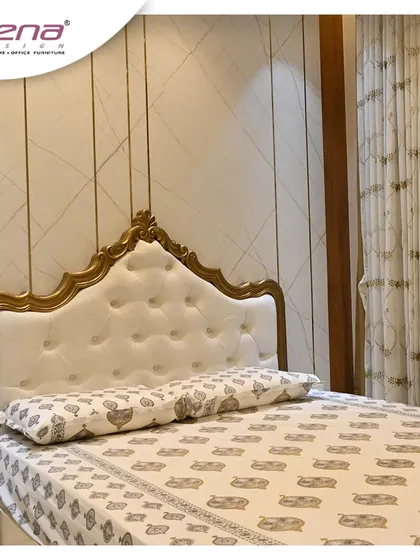 A classic and royal bedroom design, featuring a bed with an ornate, gold-finished wooden frame and a white tufted headboard.