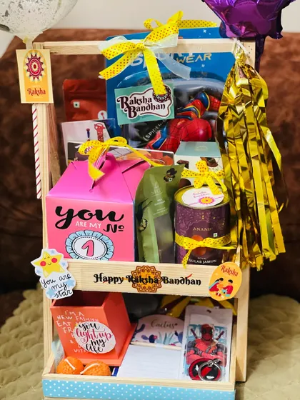 A detailed look at the contents of the two-tiered Rakhi hamper, showing snacks, gifts, and personalized "Happy Raksha Bandhan" branding.