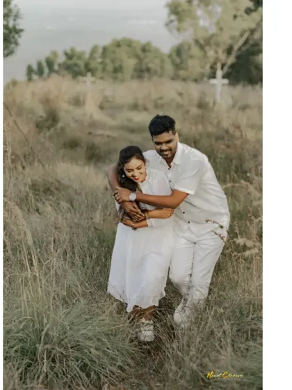 A playful and happy embrace in a field of tall grass. The couple's matching white outfits and bright smiles make this a heartwarming shot.