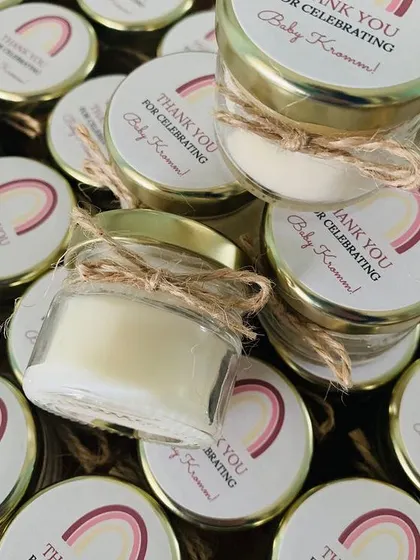 A bulk order of mini jar candles for a baby shower, customized with "Thank You for celebrating Baby Kromm!" on the labels.